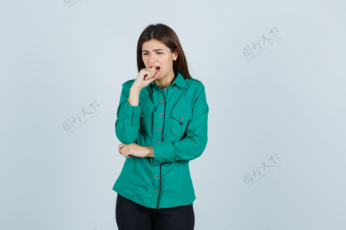 女性穿着绿色上衣 黑色裤子 愁眉苦脸地咬着手指的年轻女孩正面图模特害怕不安