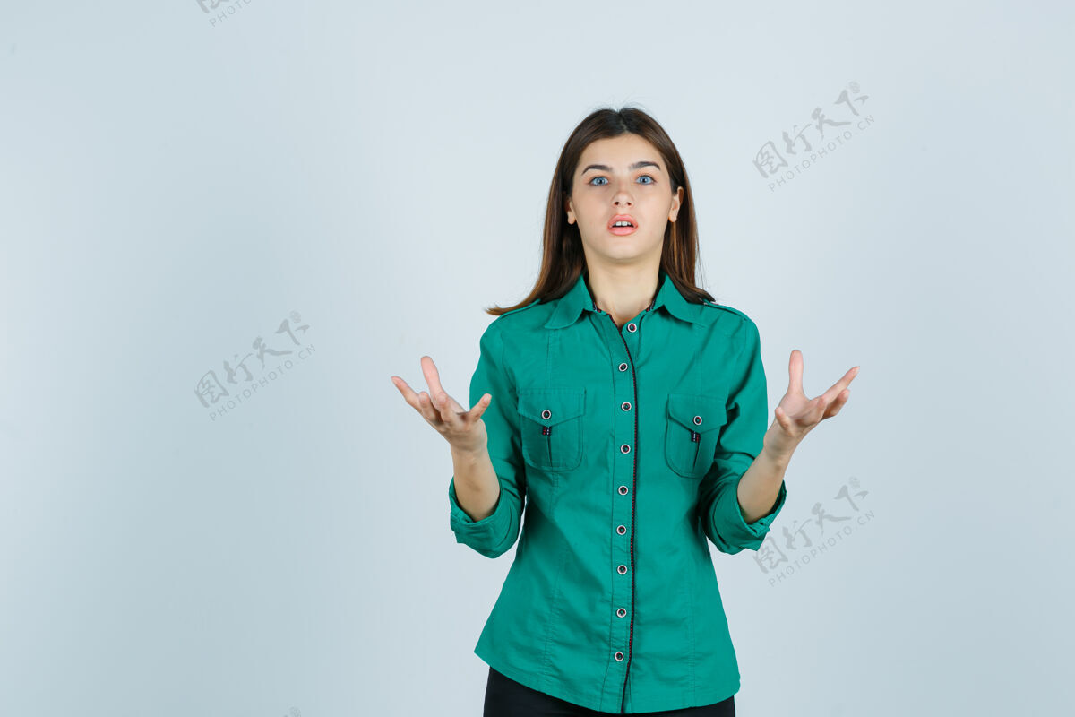 乐趣身穿绿色衬衫的年轻女性举手攻击性地看着震惊 正面视图正面商业反应