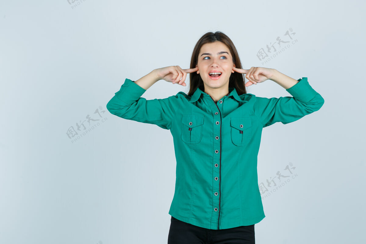 成人穿着绿衬衫的漂亮小姐用手指堵住耳朵 看上去很快乐 正对着窗外看肖像人漂亮