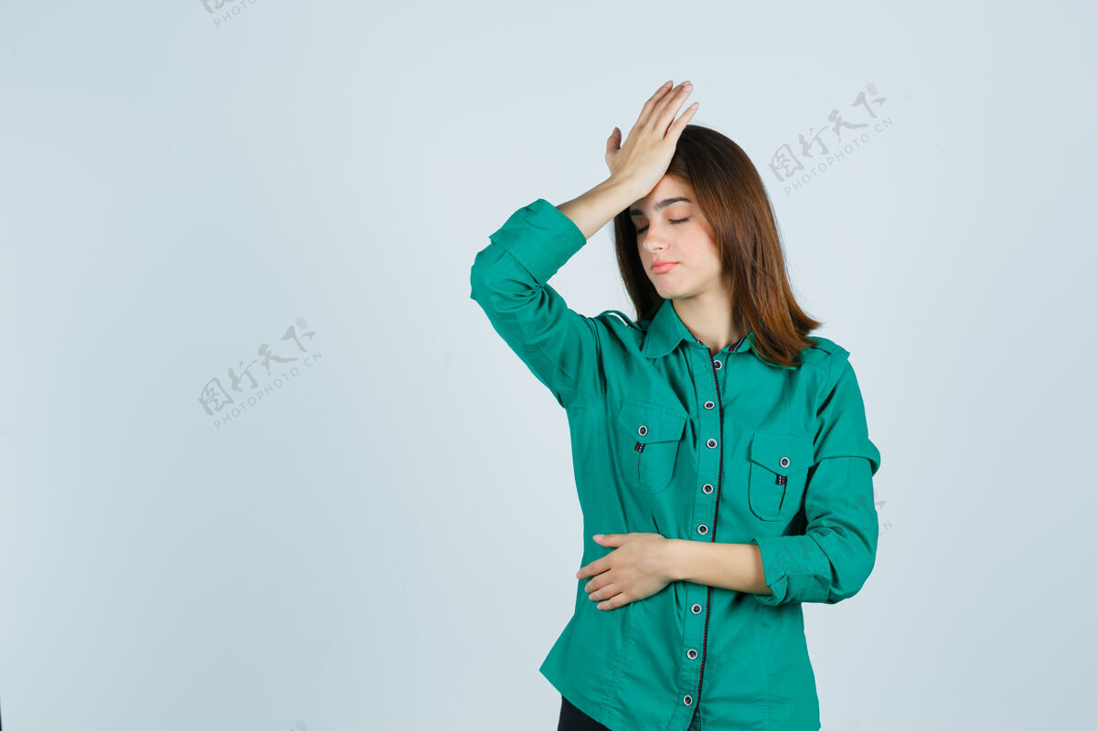 不快美丽的年轻女士的肖像感到头痛在绿色衬衫和看起来疲惫的前视图坐着疲倦年轻