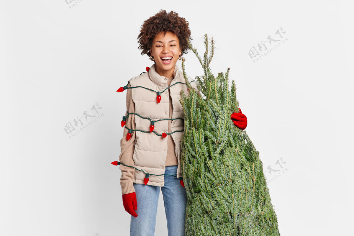 手套快乐女人带着从街市买来的刚剪好的圣诞树 用复古的花环包着节日的气氛女性包装圣诞节