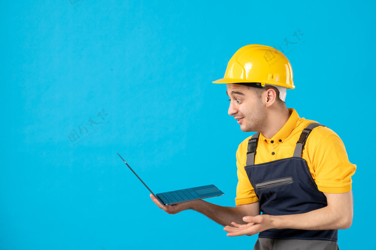 工程师穿着制服的男工人的正视图 蓝色笔记本电脑承包商职业头盔