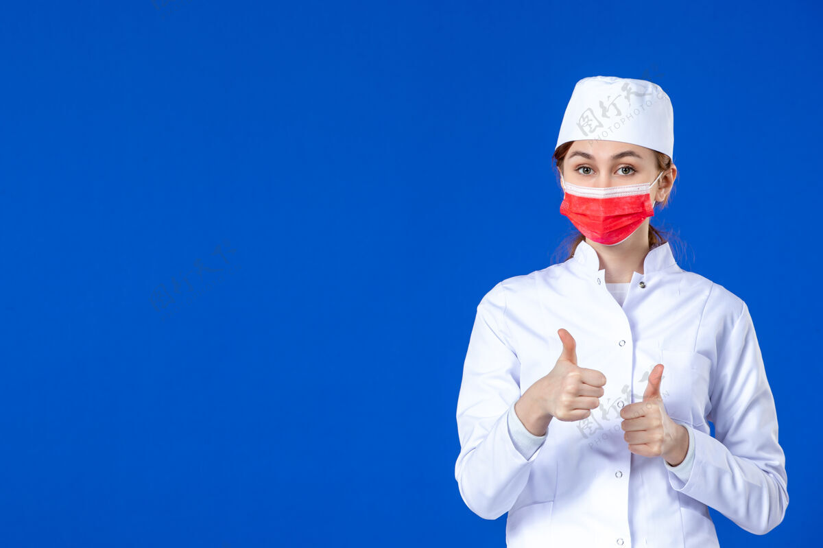 服装身穿医疗服的年轻护士的正视图 蓝色的面具上有红色的面具医学年轻护士疾病