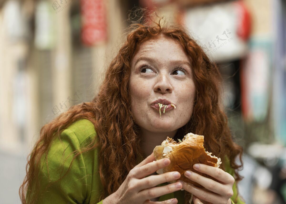 女人美女在户外吃着美味的街边小吃快餐食物都市