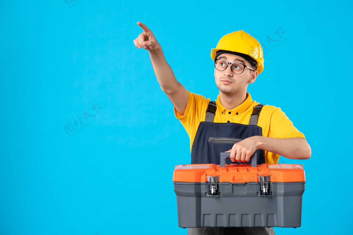 男工人身穿黄色制服的男性工人正面图 蓝色工具箱指向上方勾缝工制服表面工