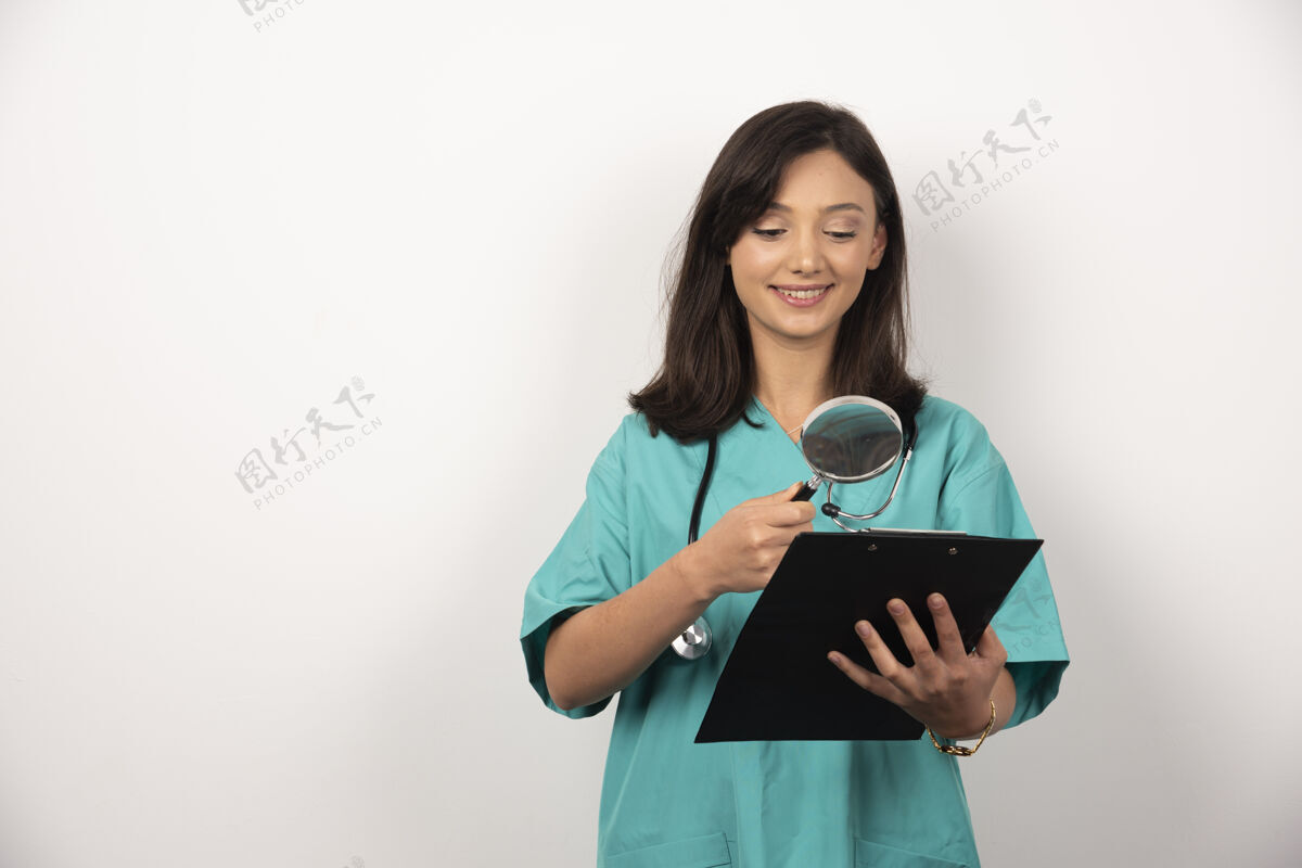 工人女医生用放大镜在白色背景上看剪贴板女性健康剪贴板