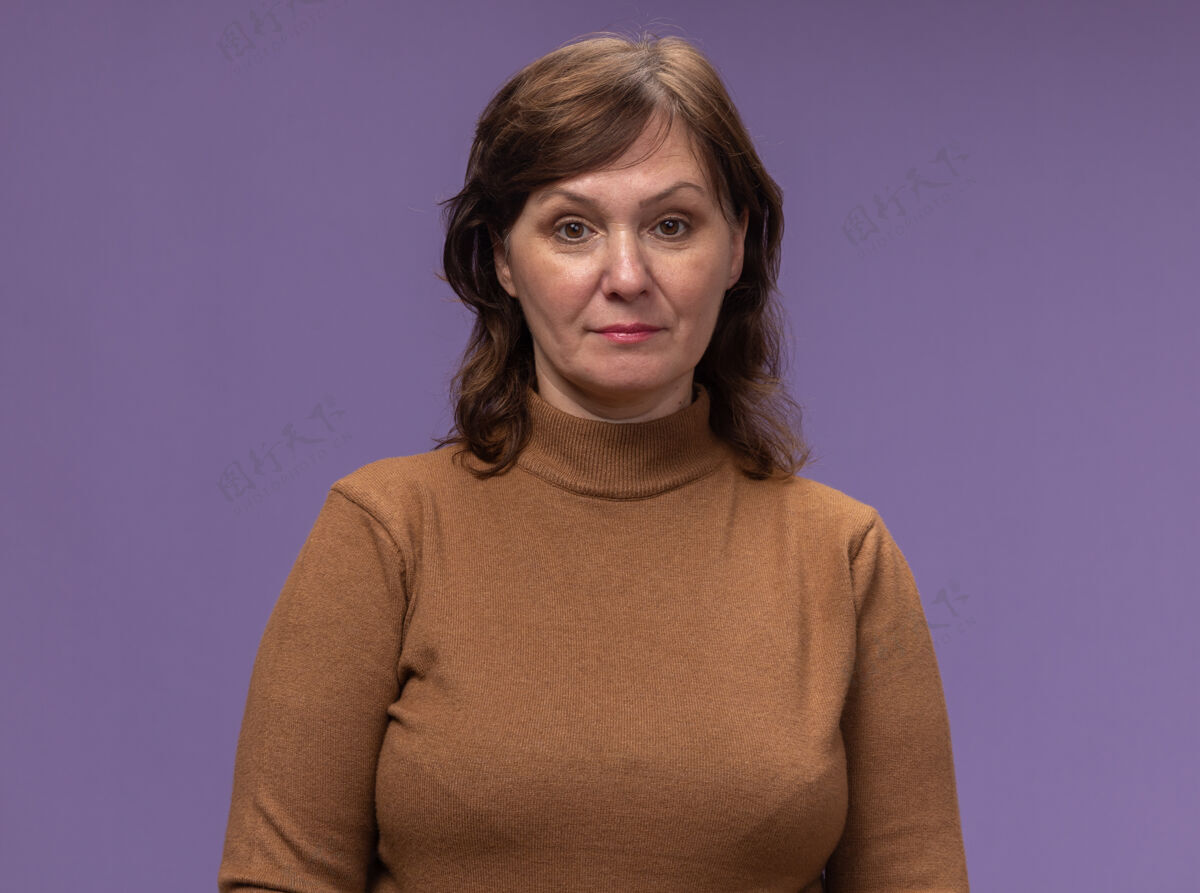 高领毛衣身穿棕色高领套头衫的中年妇女站在紫色的墙上 表情自信站姿年龄中年