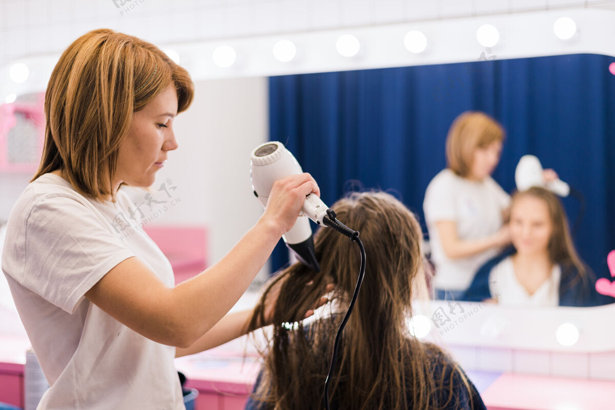 发刷专业女性美发师在美发沙龙用吹风机吹干女性发型女性梳子沙龙
