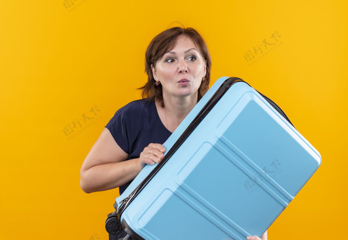 旅行看着身边牵挂着手提箱的中年旅女侧线黄色持有