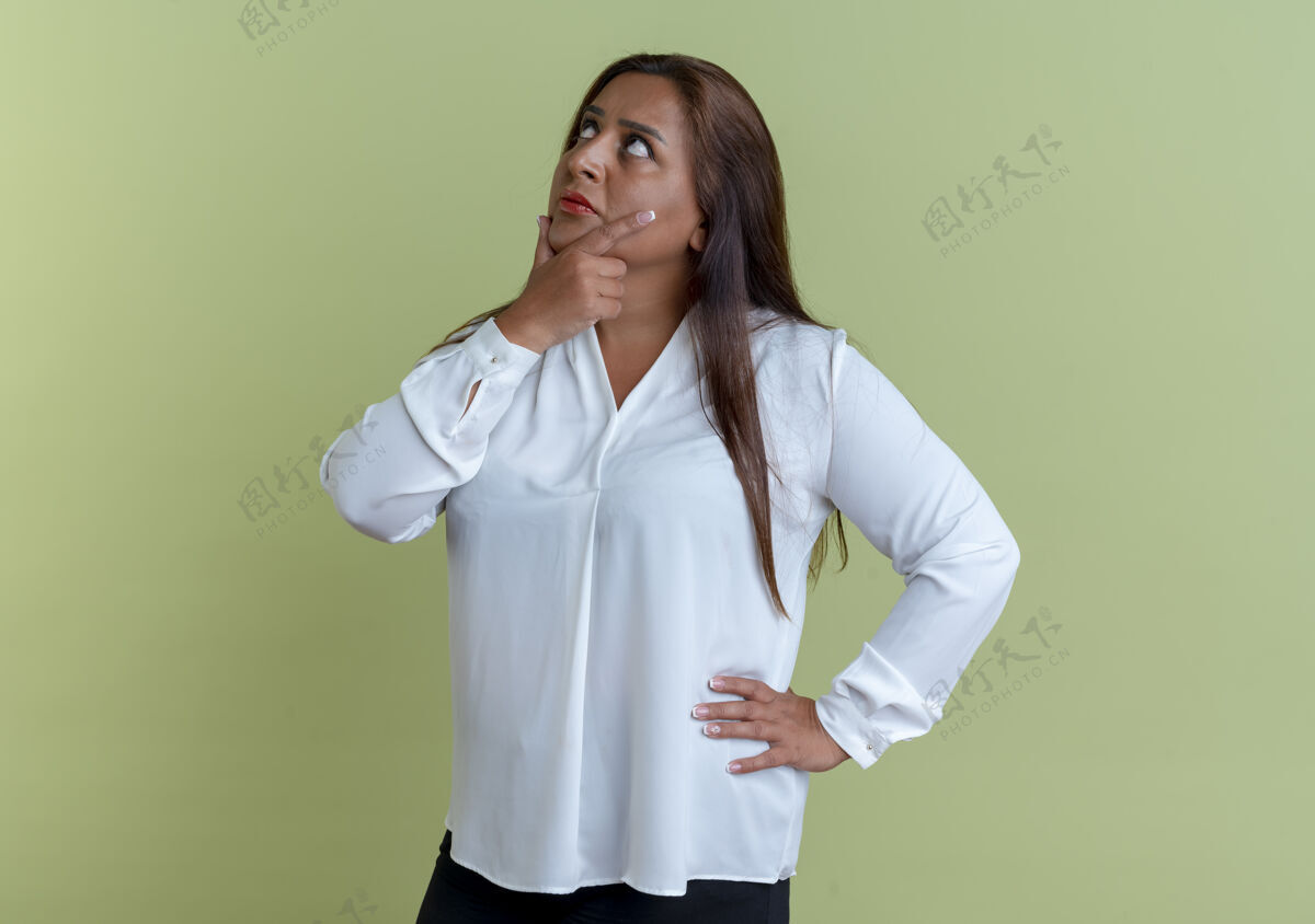 女人看着一个随和的白人中年妇女把一只手放在下巴上 另一只手放在臀部中年思考绿色
