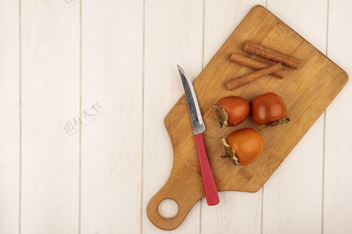 食物顶视图软柿子上的木制厨房板与肉桂棒与刀上的白色木质表面与复制空间水果新鲜健康