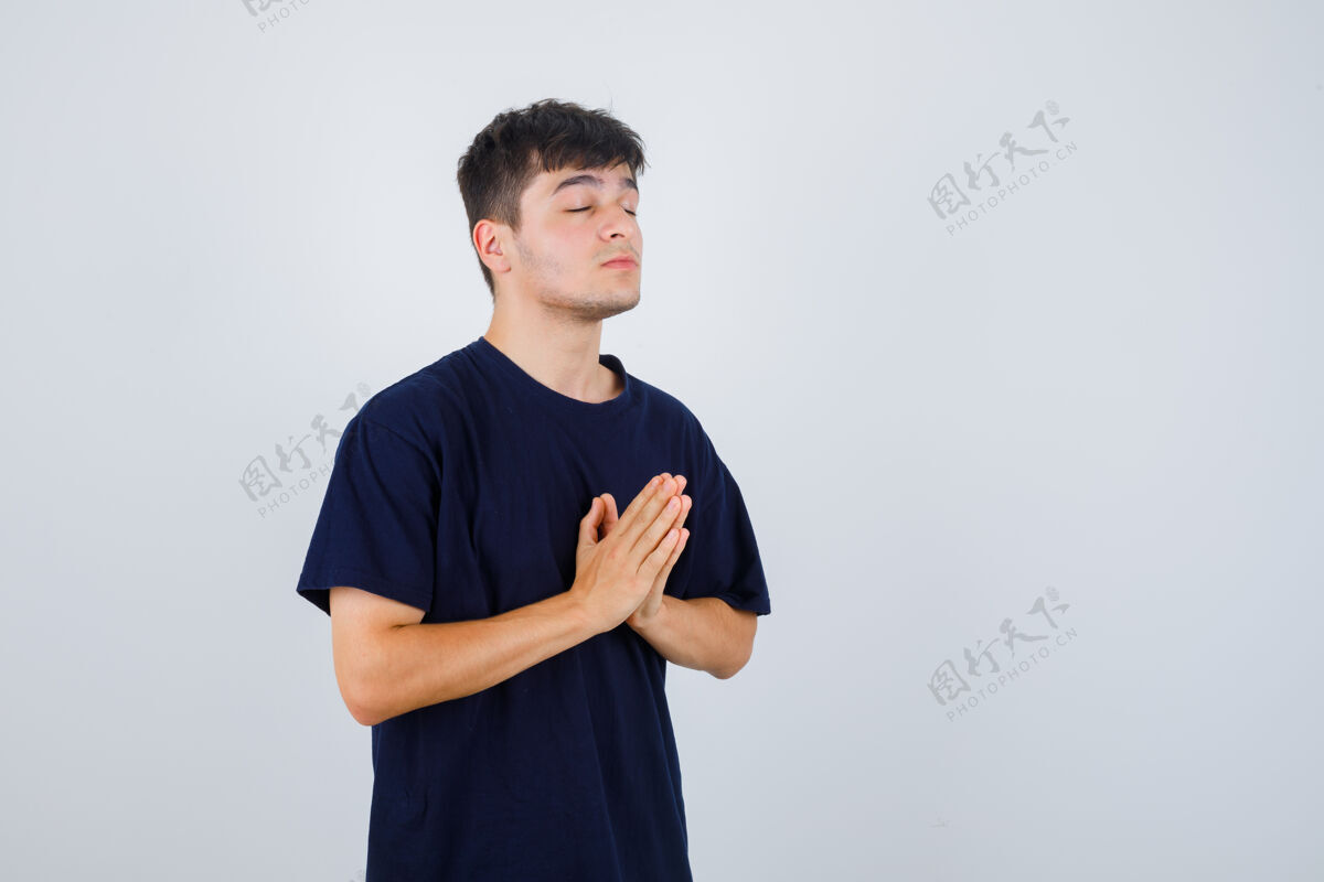基督身穿黑色t恤的年轻人 展现出迷人的姿态 看上去充满希望 正面照祈祷爱忏悔