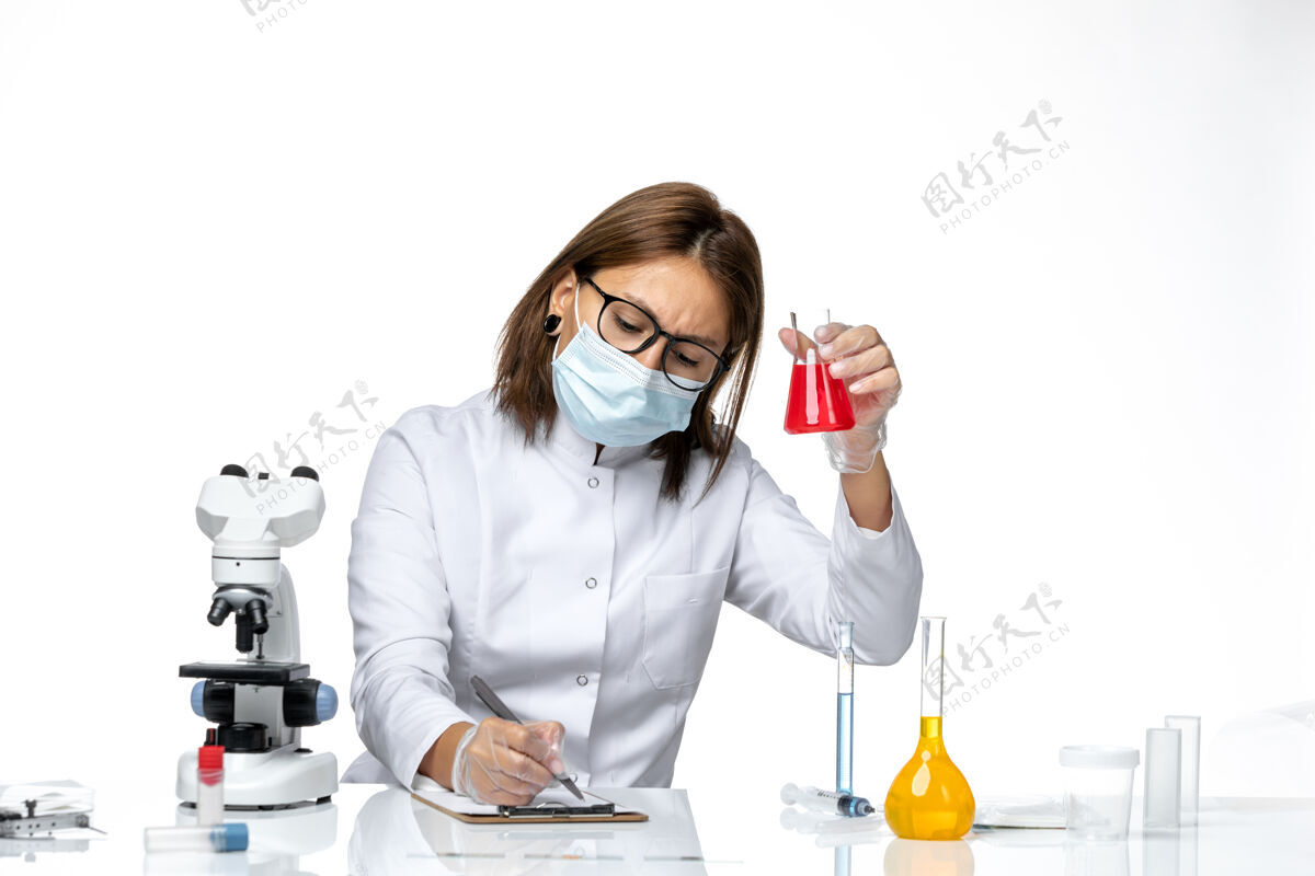 病毒前视图：女医生穿着白色医疗服 戴着面罩 在浅白色空间写笔记女医生浅白色便条