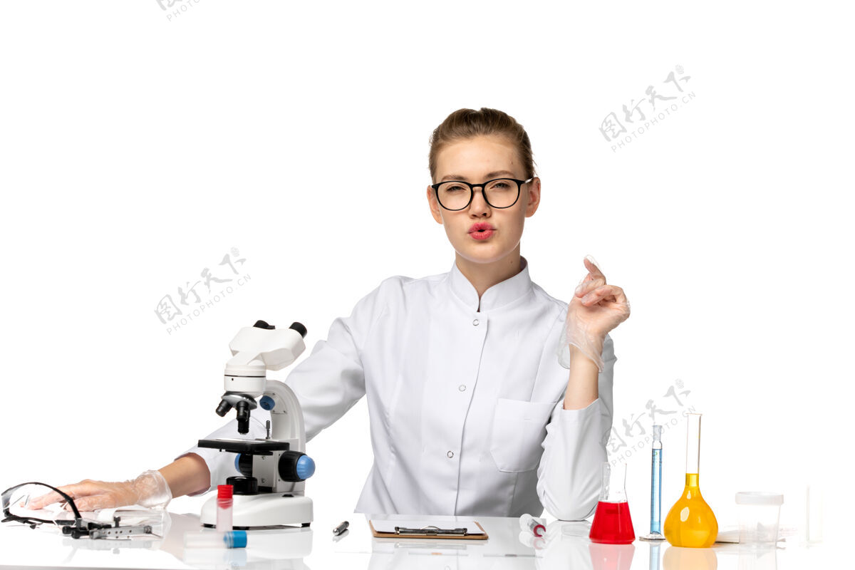 女医生前视图穿着白色医疗服的女医生坐在桌子前 在浅白的空间里解决问题病毒桌子西装