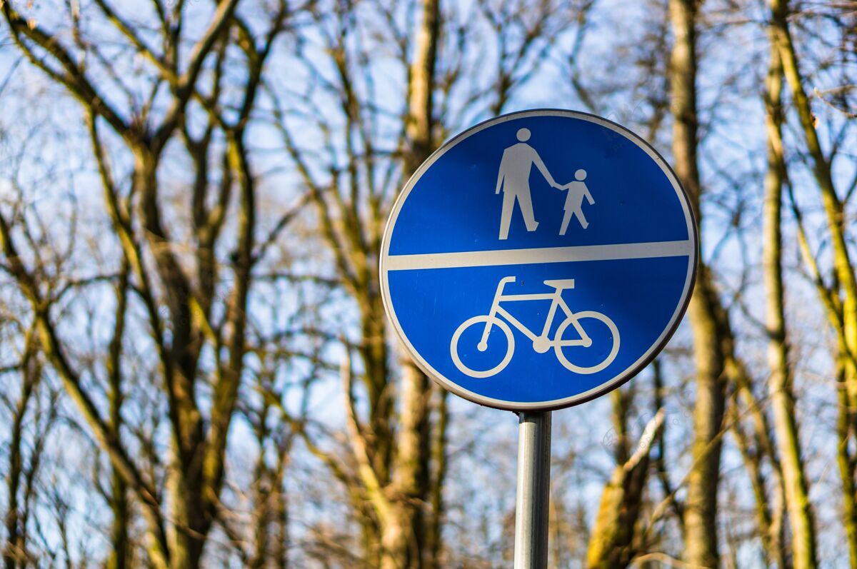 街道特写的蓝色路标下的人和自行车的阳光与模糊的背景自行车自然自行车手