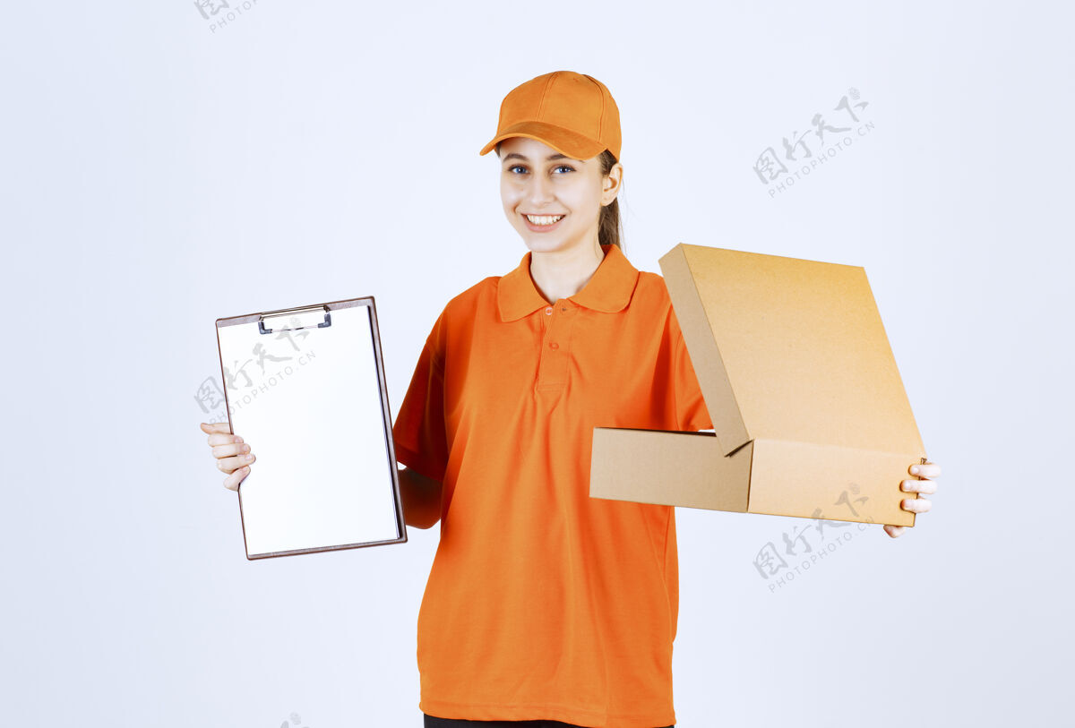 姿势穿着橙色制服的女信使拿着一个打开的纸板箱 要求签名清单订单食品