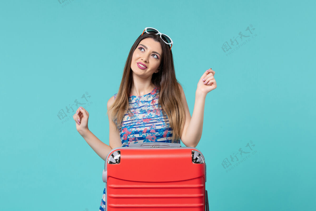 漂亮前视图美丽的女性准备度假与浅蓝色空间上的红色袋子海性感包