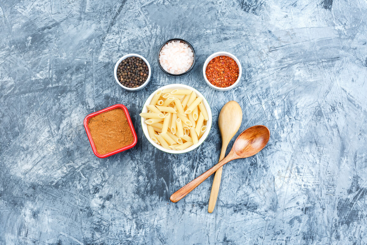 传统顶视图白色碗中的佩恩面食 带木勺 灰色灰泥背景上有香料水平餐厅石膏通心粉