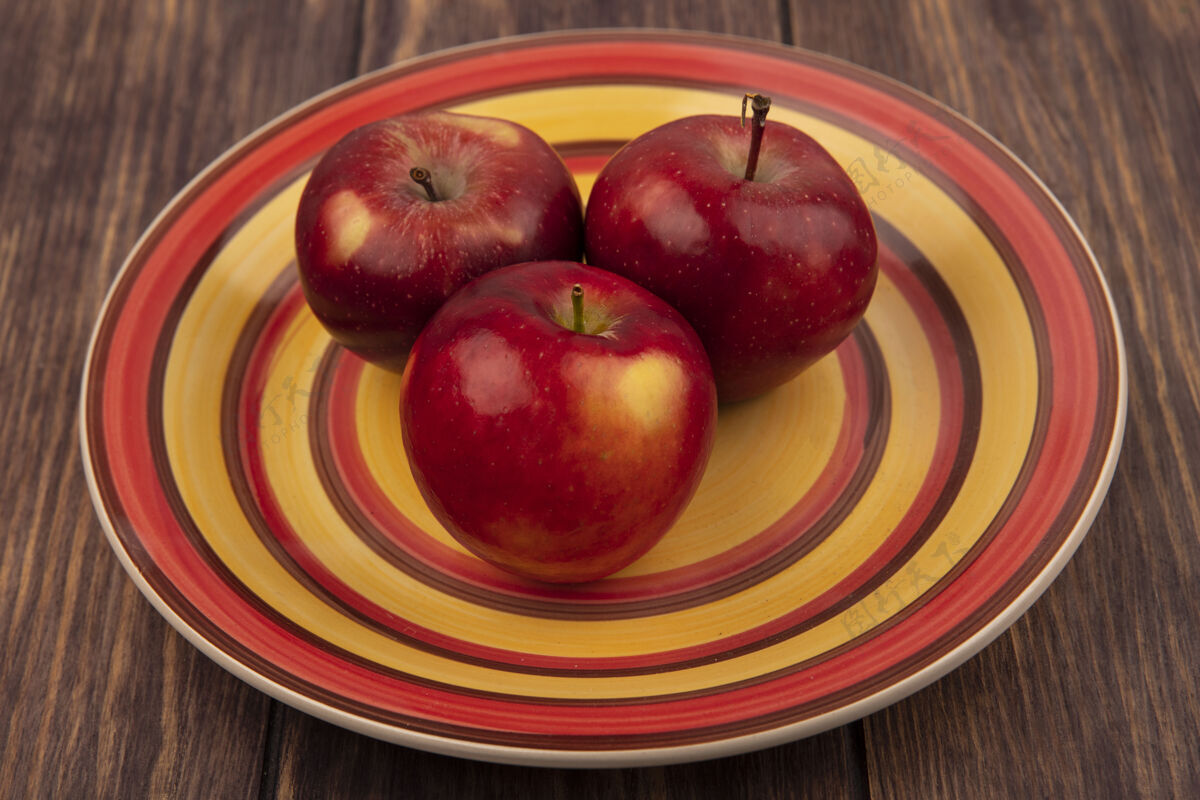 食品木头表面盘子上美味的红苹果俯视图木头盘子美味