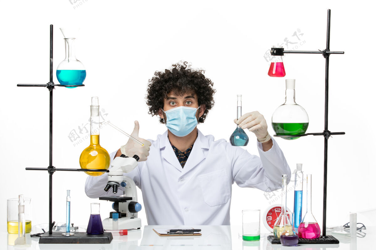 手持正面图男性化学家穿着白色的医疗服 戴着面罩 在白色的空间里拿着蓝色的溶液化学外套医学