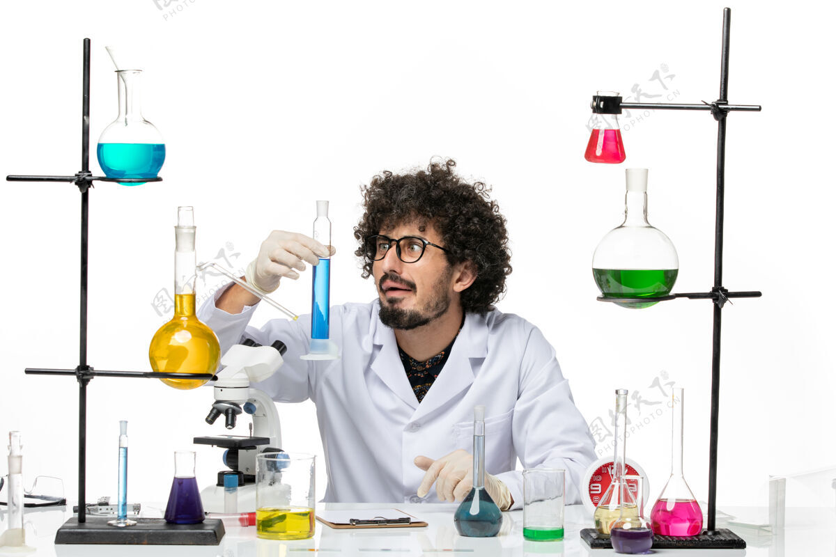 烧杯正面图身穿医疗服的男性化学家拿着蓝色溶液在白色空间外套科学实验室