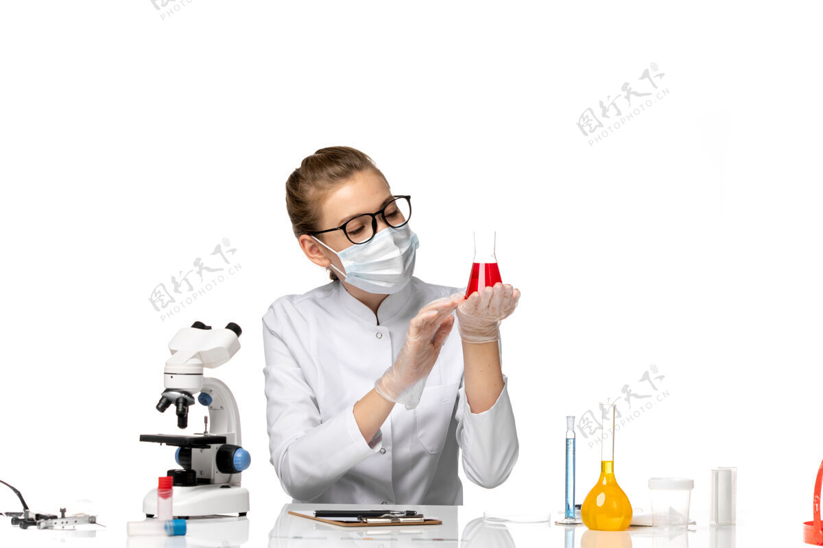 前台正面图：女医生穿着医疗服 戴着面罩 因为科维德在白色办公桌上用溶液工作到期病毒面罩