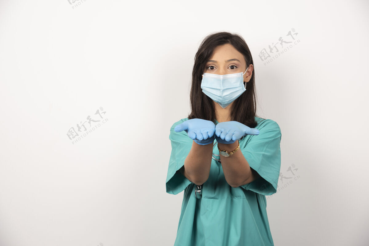 职业戴着医用口罩和手套的年轻医生在白色背景上张开双手健康手套工人