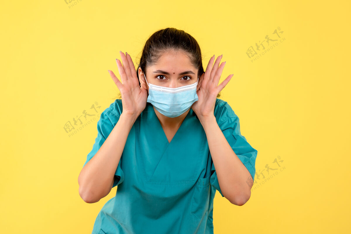 健康黄色墙壁上戴着医用面罩的漂亮女医生的正视图人人支持