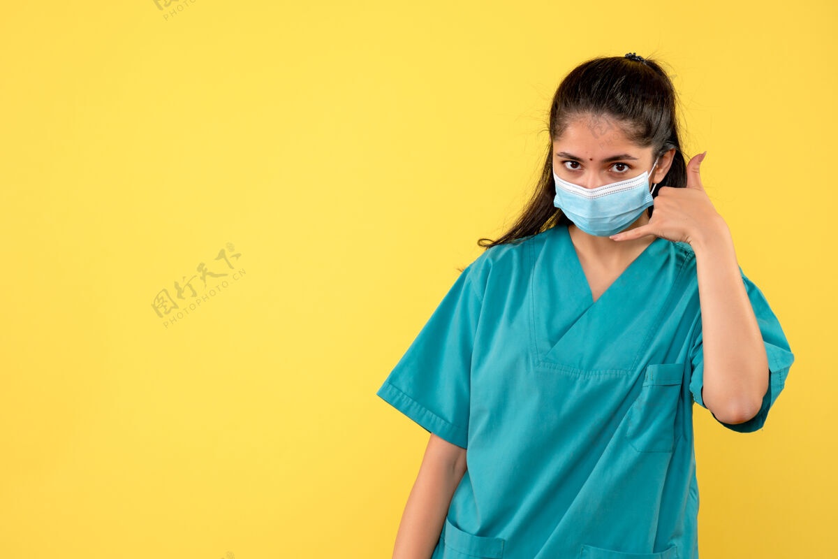 人黄色墙上戴着医用面罩的漂亮女医生打电话给我的标志面具医学正面