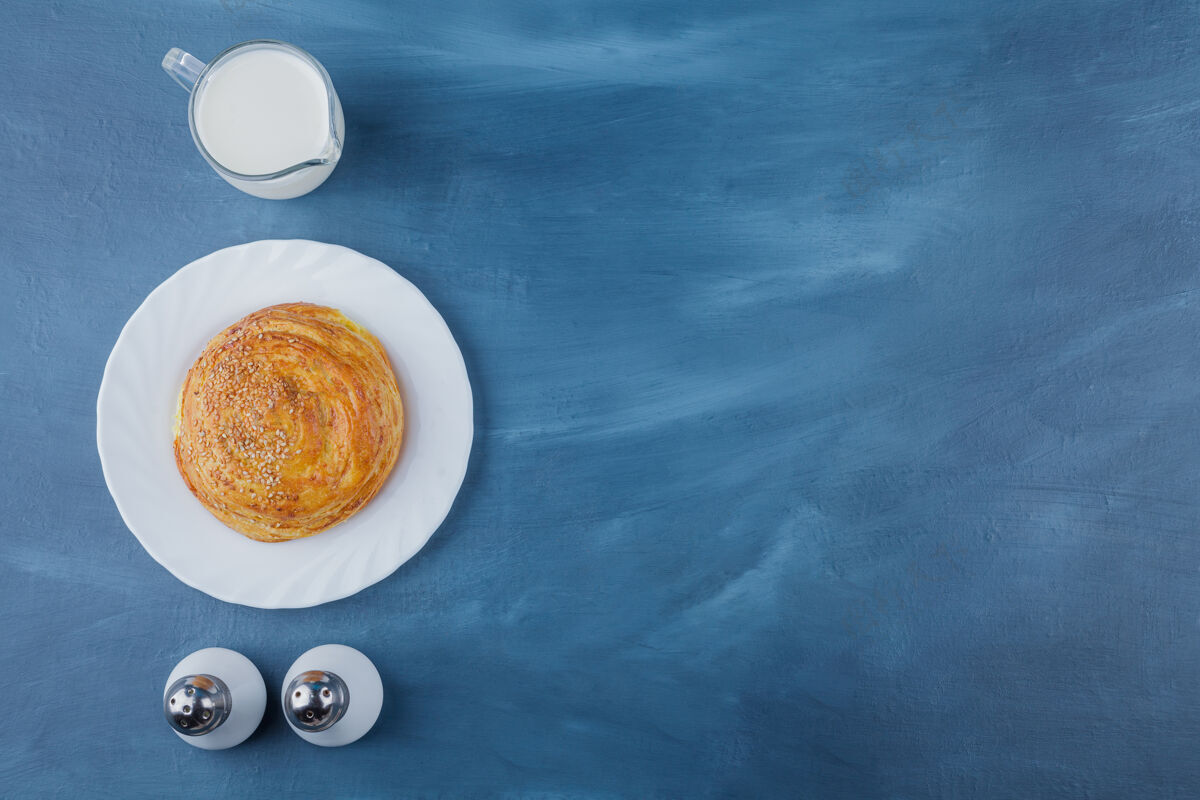 有机一盘新鲜的圆形糕点 蓝色表面上有鲜奶谷类面包面包