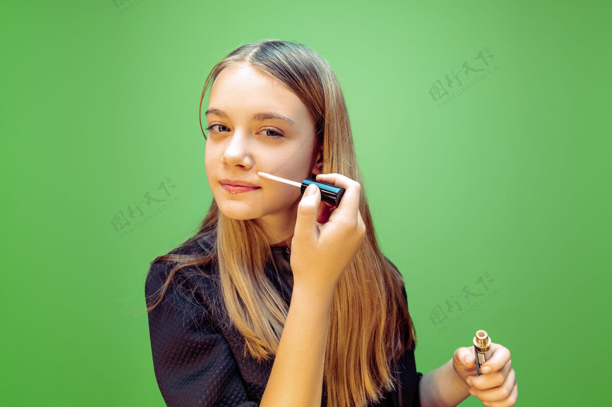 化妆女孩在绿色上涂唇膏成功表演青春