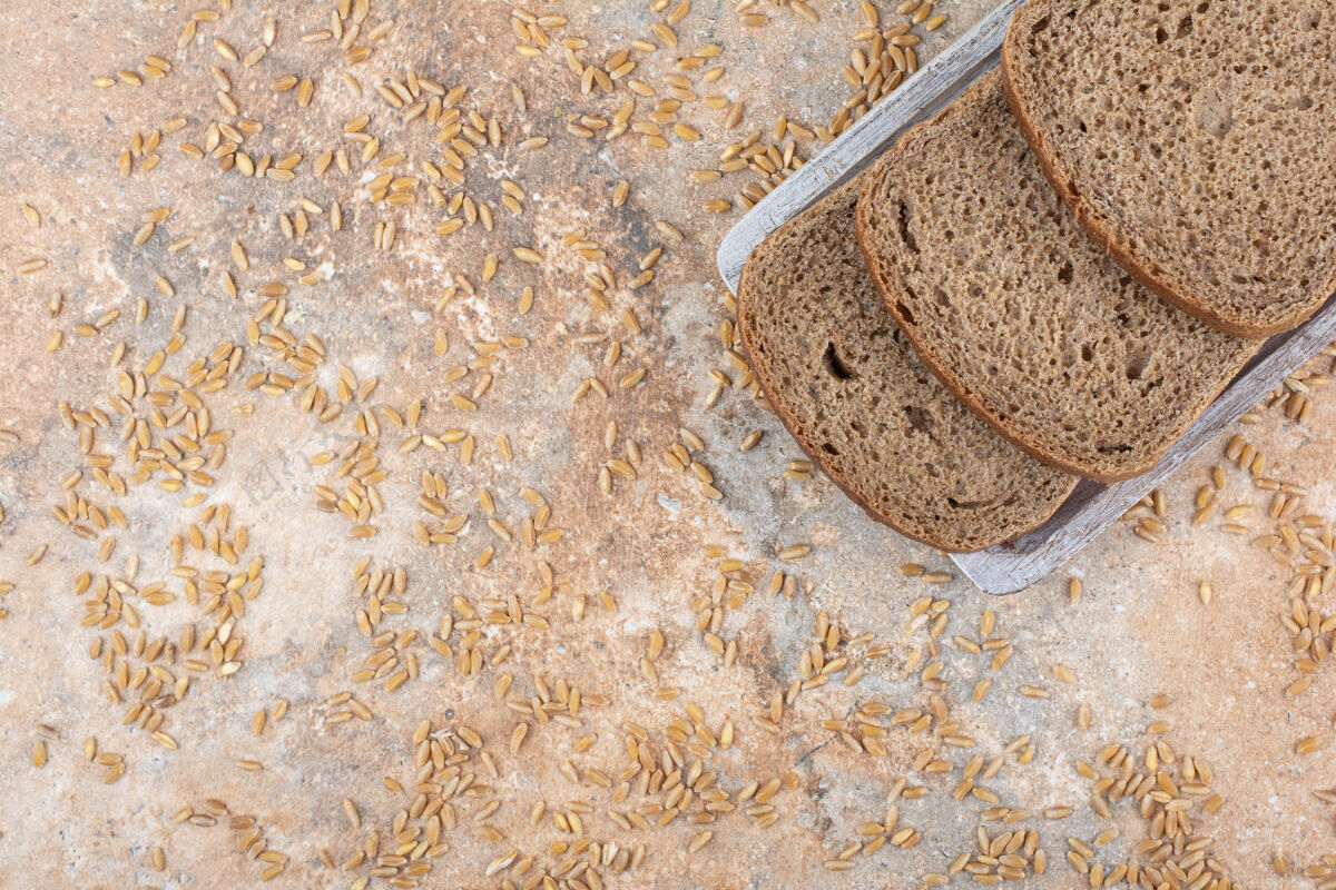 谷类黑面包片和大麦粒在大理石表面谷物自制面包房
