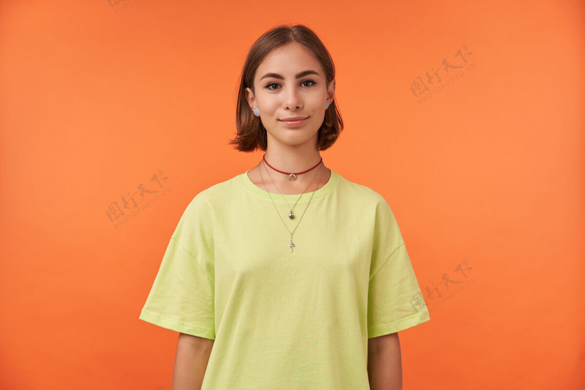 休闲女学生 迷人的年轻女士 深色短发 自信地穿着绿色t恤 戴着项链和耳环20多岁时尚女士
