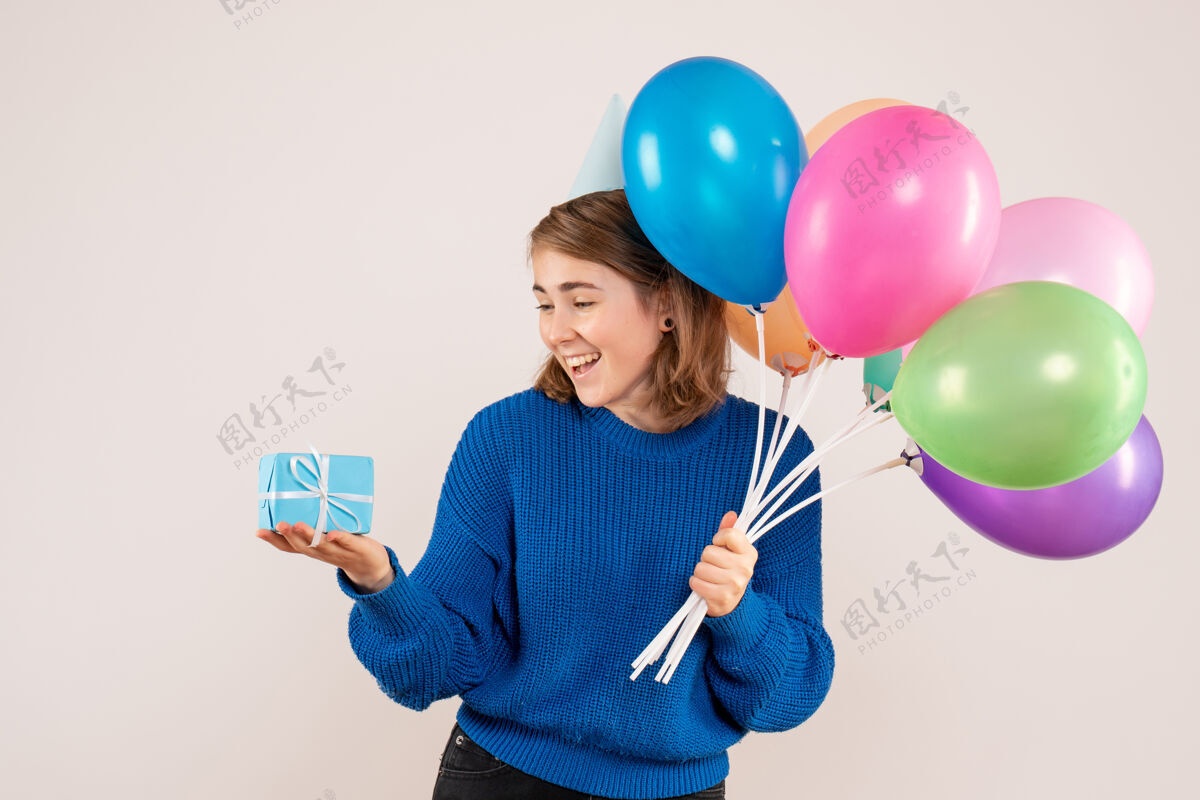 观点手持彩色气球和白色小礼物的年轻女性生日乐趣聚会
