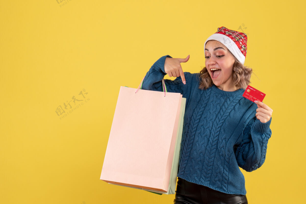 笔记本电脑年轻女子持银行卡和包裹购物后上黄色圣诞节银行电脑