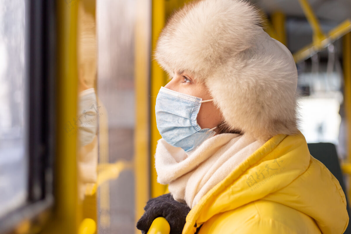 衣服一个穿着暖和衣服的年轻女子在一个冬天的城市公共汽车上的明亮的阳光肖像女性公共汽车公共汽车站