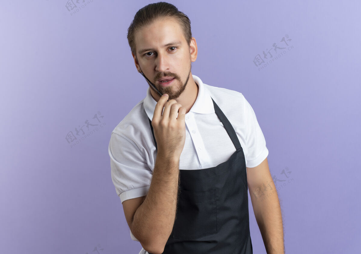 自信自信的年轻帅哥理发师穿着制服梳着胡子 隔离在紫色的复制空间里空间制服帅气