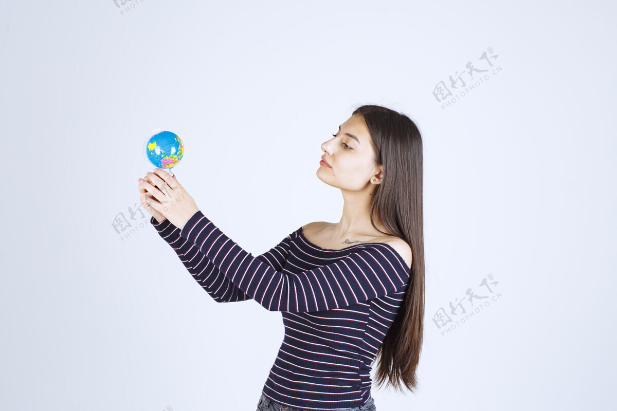 女性穿着条纹衬衫的年轻女子拿着一个迷你地球仪 看起来很兴奋人类刺激人
