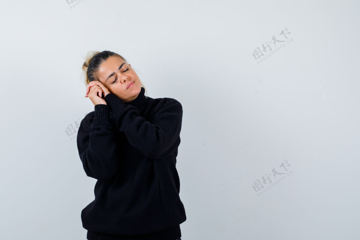 人年轻的女性枕着脸 双手合十 穿着黑色高领毛衣 看起来很困倦正面图手打哈欠疲劳