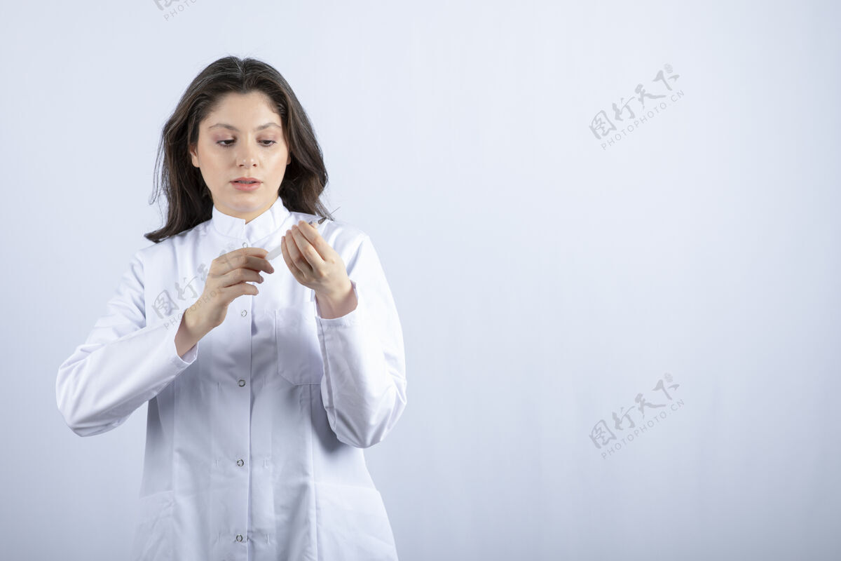 持有年轻的医生拿着注射器准备在白墙上注射注射器医学年轻