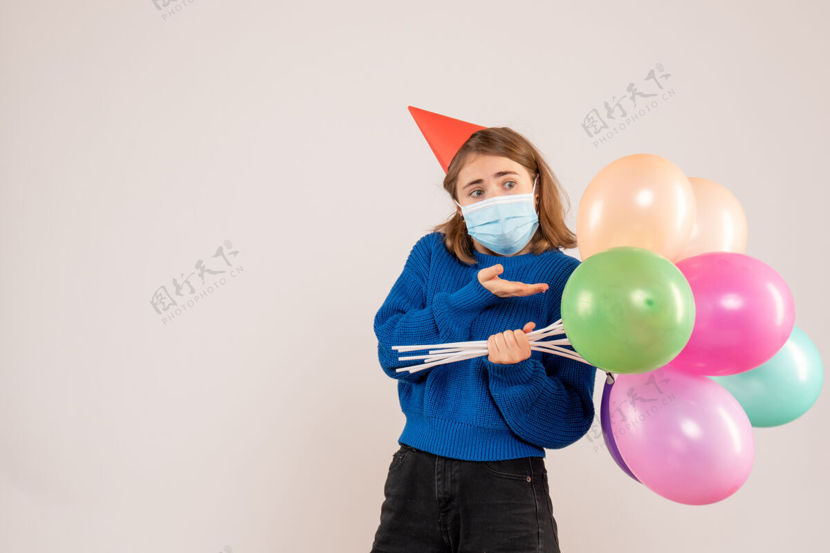 面具戴着白色面具手持彩色气球的年轻女性气球情感年轻女性