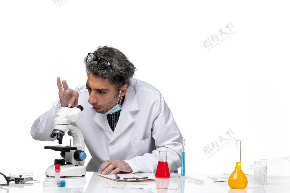 正面穿着白色医疗服的中年科学家使用显微镜的正视图显微镜实验室技师