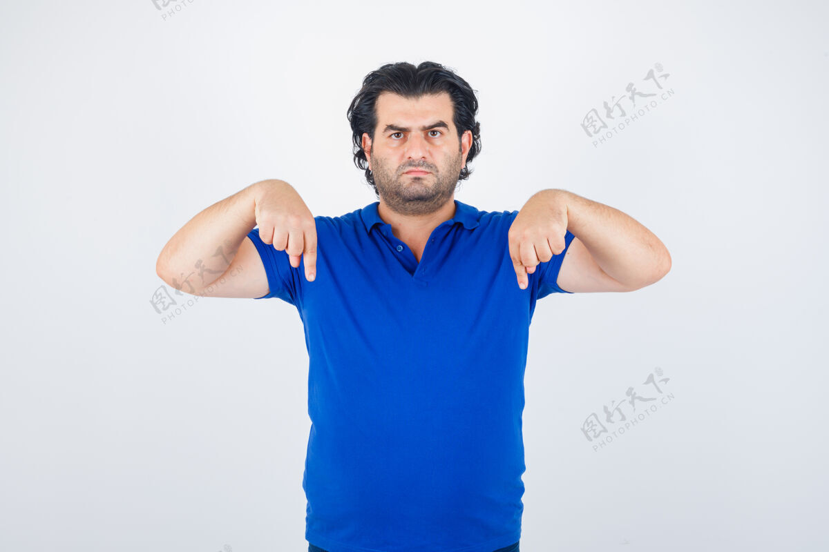 愤怒成熟的男人用食指指着下面 穿着蓝色t恤 牛仔裤 看起来很生气 正面照指向侵略性负面