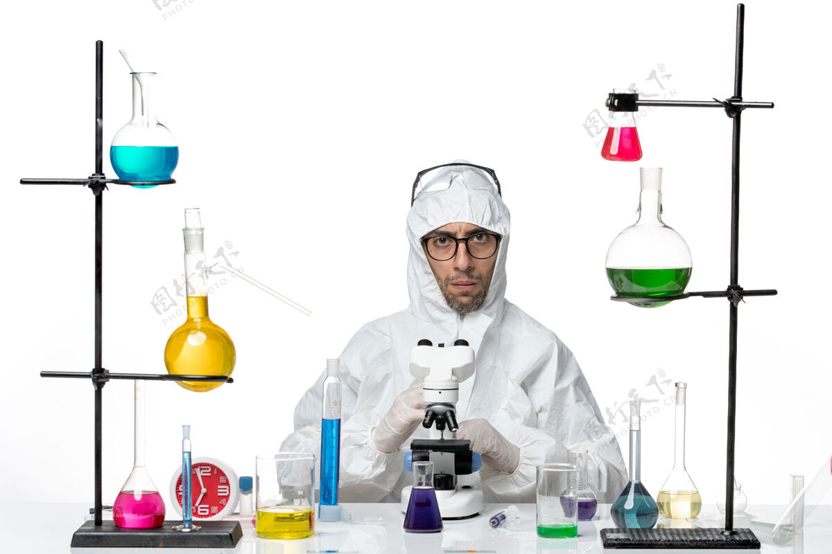 化学品前视图穿着特殊防护服的男性科学家使用显微镜正面使用实验室