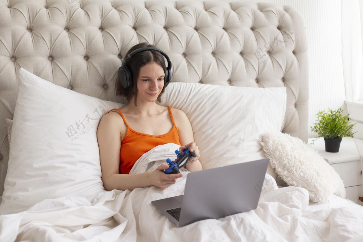 控制台女人在床上玩电子游戏玩家娱乐数字