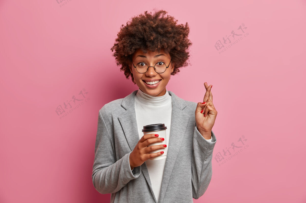 优雅快乐的美国黑人商务女士在重要活动前交叉手指 端着外卖咖啡 全力以赴祈祷 希望成功漂亮肖像希望