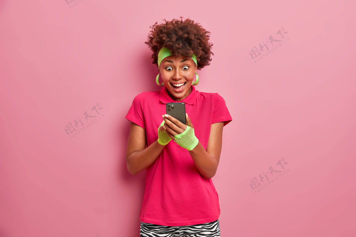 时尚兴奋快乐的女人在智能手机屏幕上幸福地凝视着满意积极休闲