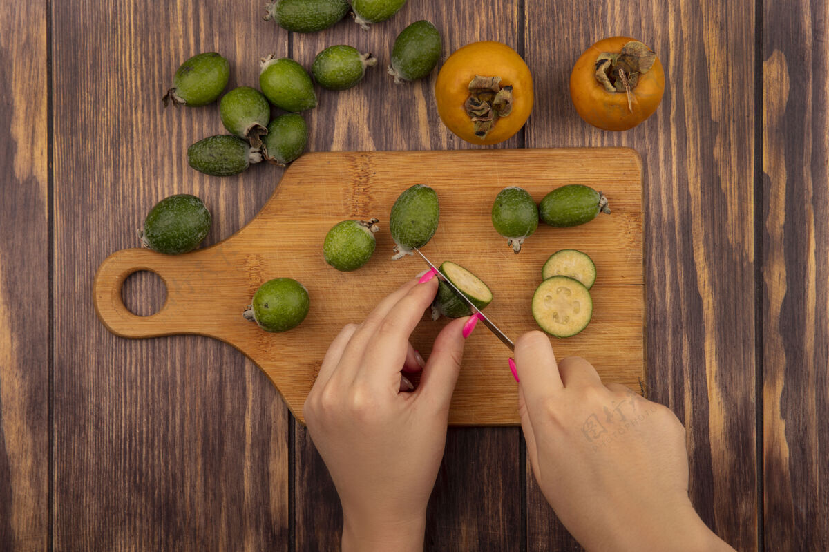 刀女性用刀在木制厨房板上切割飞珠的俯视图 新鲜的柿子和飞珠被隔离在木制墙上水果厨房鲜