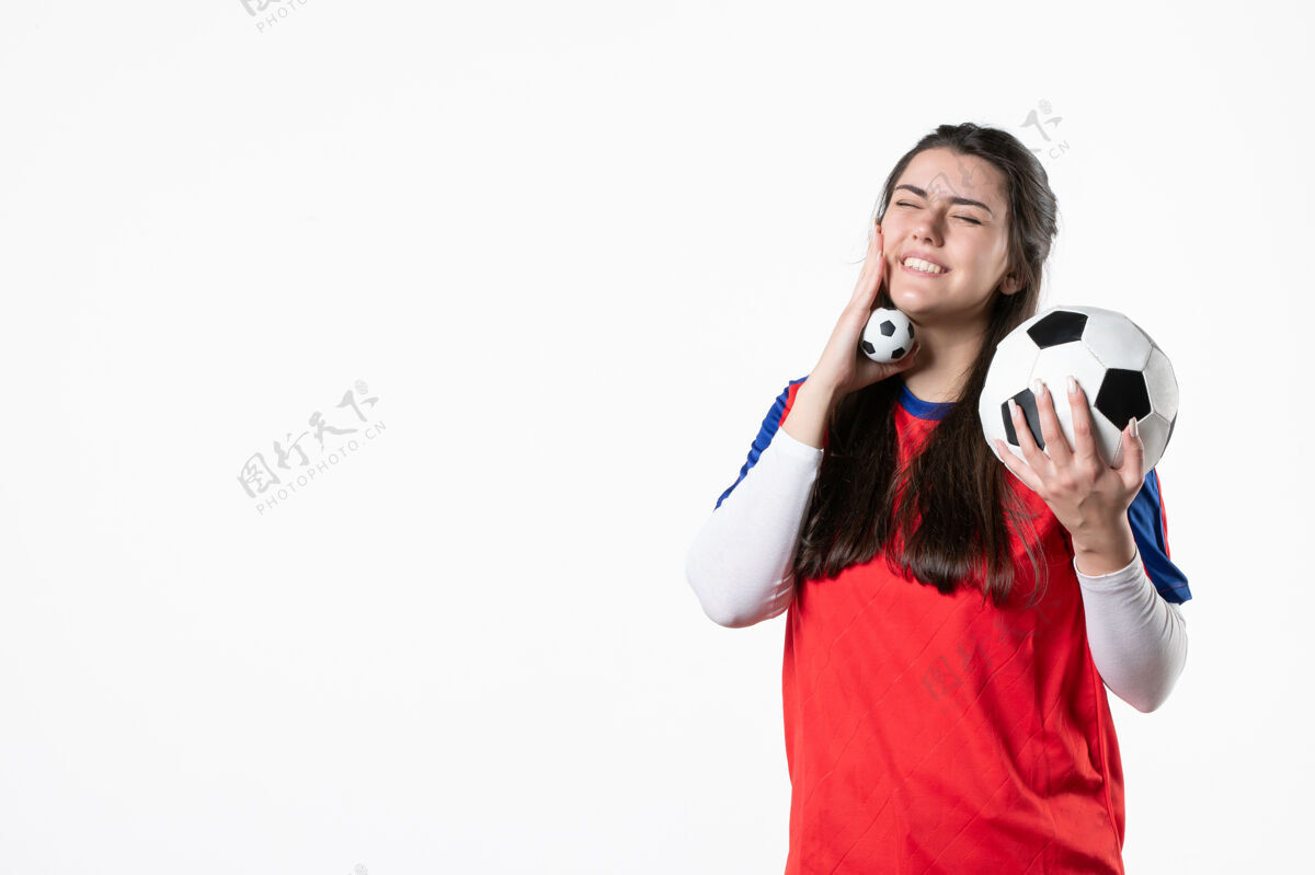 视图前视图穿着运动服的年轻女性 白色墙壁上有足球肖像前面微笑