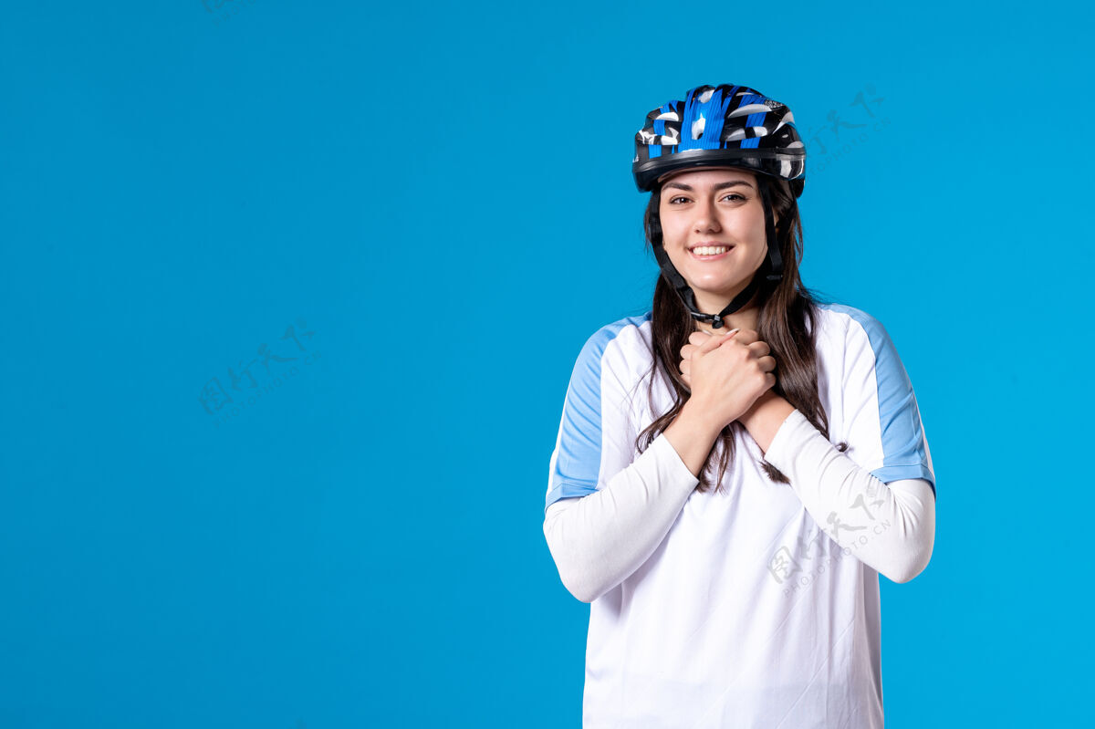成人前视图穿着运动服的年轻女性 蓝色墙上戴着头盔蓝色运动视图